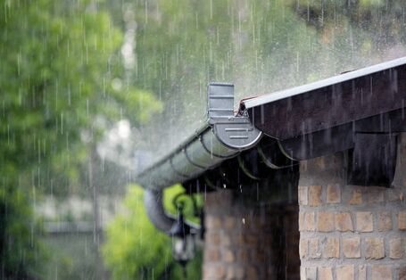 The picture shows the rainwater gutter of a brick building. Heavy rain is falling.