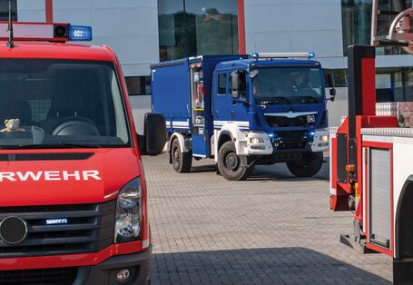 Das Bild zeigt zwei Einsatzfahrzeuge mit angeschaltetem Blaulicht, ein rotes der Feuerwehr und ein blaues des Technischen Hilfswerks. Beide Fahrzeuge sind nur in Teilen zu sehen.