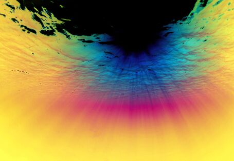 Das Bild zeigt den Blick von unter Wasser auf die Meeresoberfläche. Die Sonne strahlt durch die Wasseroberfläche hindurch. Das Meer hat eine dunkelblaue bis türkisgrüne Farbe.