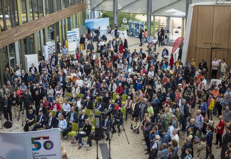 Ein Foto aus der Vogelperspektive vom Jubiläumsfest am 15.06.2024 in Dessau-Roßlau mit vielen Gästen, die im Forum des Umweltbundesamtes stehen. 