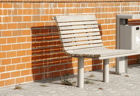 Das Bild zeigt eine Bank aus unbehandeltem Holz mit einem Unterbau aus Metall, der verhindert, dass das Holz Bodenkontakt hat.