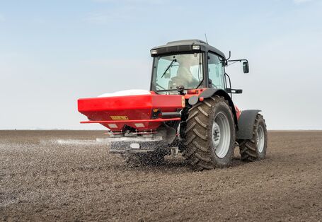 Ein Feld mit einem Dünger-Fahrzeug, um das Feld zu düngen 