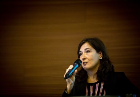 Moderatorin spricht auf dem Podium ins Handmikro