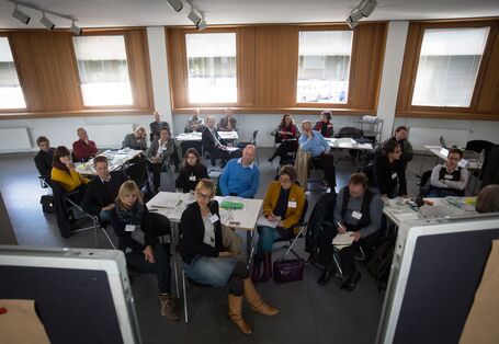 Teilnehmer sitzen an Arbeitsgruppentischen
