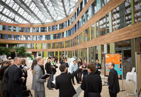 Teilnehmer stehen im Forum des Umweltbundesamtes an einer Präsentationsinsel