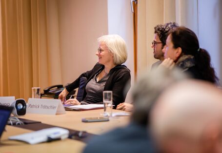 Teilnehmende sitzen im Workshopraum zusammen und schauen zuhörend in eine Richtung in einem hellen Raum.