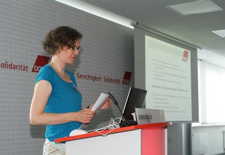 Vortragende steht am Rednerpult und schaut auf das Manuskript in den Händen.