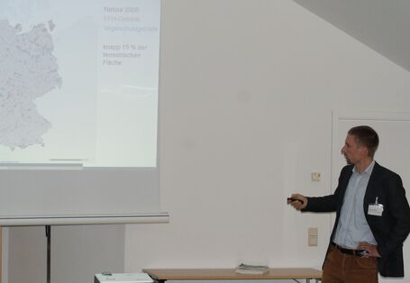 Teilnehmer trägt vor zu Vogelschutzgebieten und zeigt mit dem Pointer in der Hand auf die Deutschlandkarte.