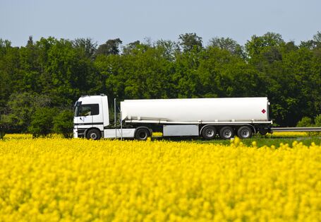 Weißer Tankwagen auf einem Rapsfeld