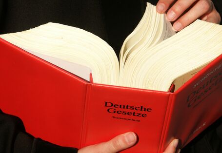 Ein dickes rotes Gesetzbuch, dass umgeblättert wird.