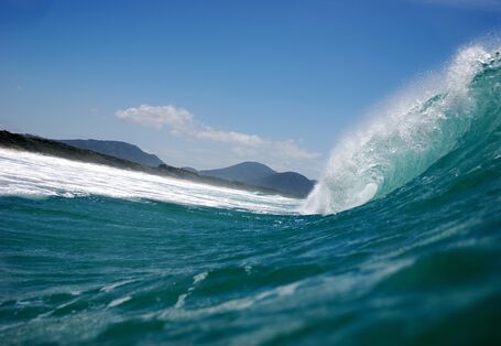 Nahaufnahme einer großen Welle, die kurz davor ist in die Brandung zu stürzen