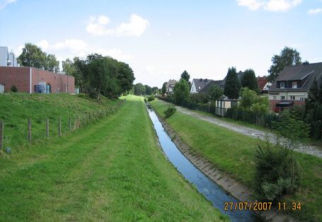 Ein Bach fließt im Grünen am Ortsrand entlang