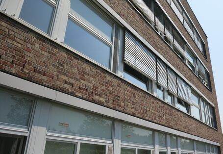 Ein vierstöckiges Haus mit großen Fenstern und Sonnenrollos