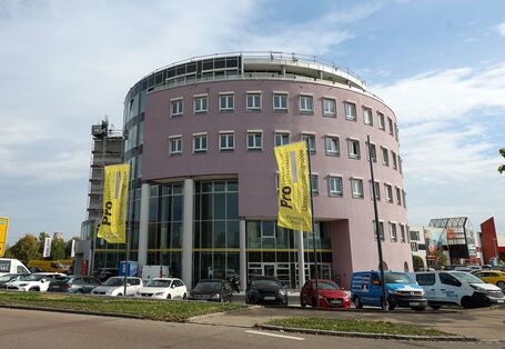 Das sechsstöckige Bürogebäude Sternodrom mit rundem Grundriss von außen. Vor dem Gebäude wehen Fahnen.