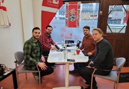 Das Bild zeigt vier Personen, u.a. Timo Hildebrand, am Tisch bei einer Podcast-Aufnahme. Der Blick geht hinaus durch die Schaufensterscheibe des Ladenbüros auf die andere Häuserseite.