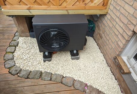 Das Außengerät einer Wärmepumpe vor einem Haus.