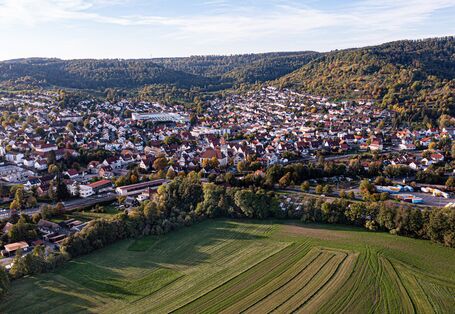 Blick aus der Vogelsperspektive über die Gemeinde Rudersberg. Vorne befindet sich ein großes Feld und im Hintergrund Hügel.