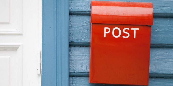 Ein roter Briefkasten hängt an einer Hauswand