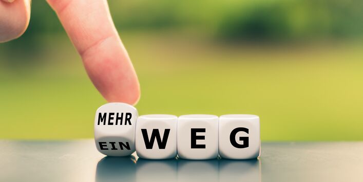 Hand dreht einen Würfel und ändert das Wort Einweg in Mehrweg