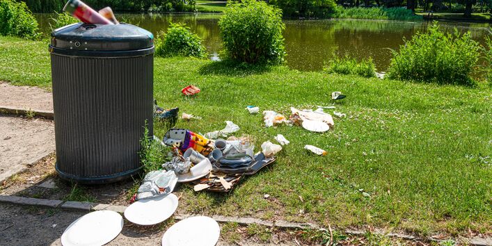 Plastikmüll Picknikartikel quellen aus einer Mülltonne im Park