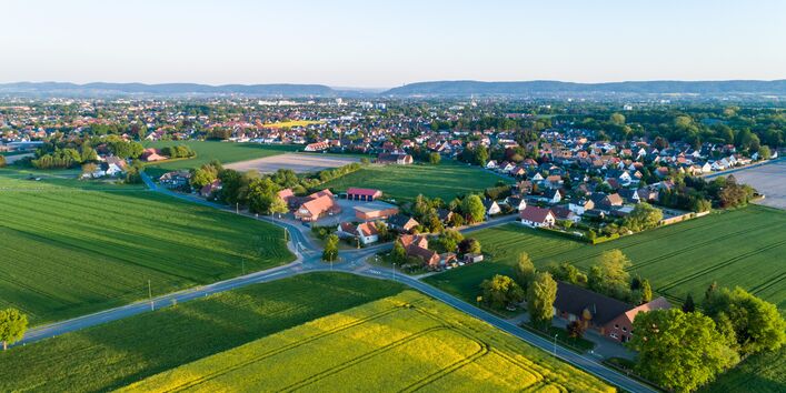 Luftbild einer ländlichen Siedlung zwischen Feldern.