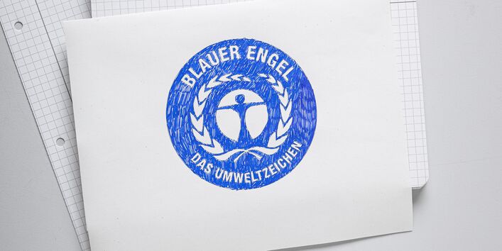 Auf einem Blatt Papier wurde das Umweltzeichen Blauer Engel gemalt.