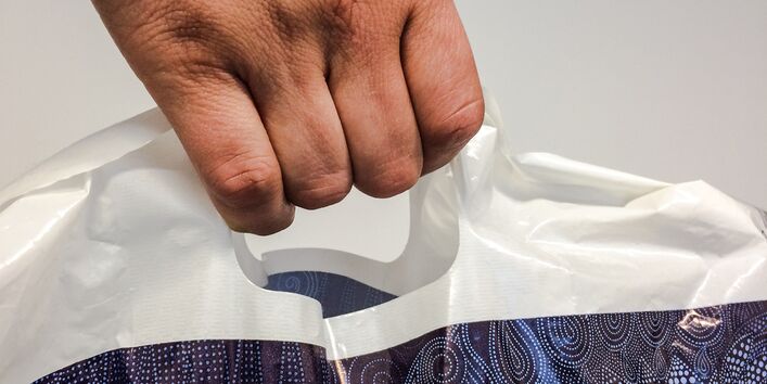 Mensch hält Plastiktüte in der Hand