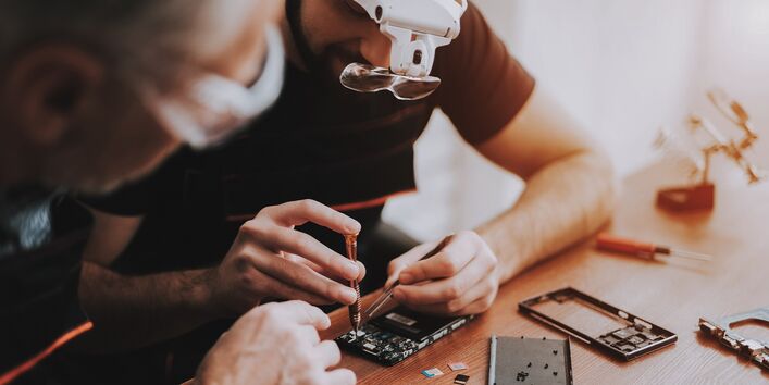 Zwei Menschen reparieren ein Elektrogerät.