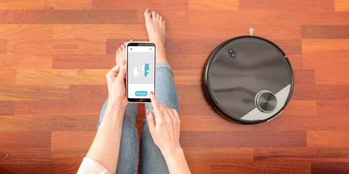 Frau bedient Saugroboter über Handy-App