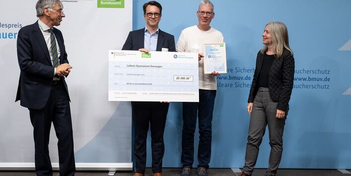 Stefan Tidow und Dr. Bettina Rechenberg überreichen einen Scheck an die Gewinner des des Community-Preises. 