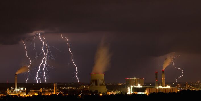Das Bild zeigt Blitze über einer industriellen Anlage.