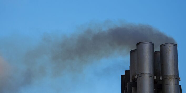 Ein Schornstein stößt dunklen Qualm aus.