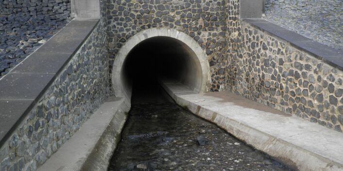 Entrance of a stream into a pipe. The banks and the riverbed are concreted.