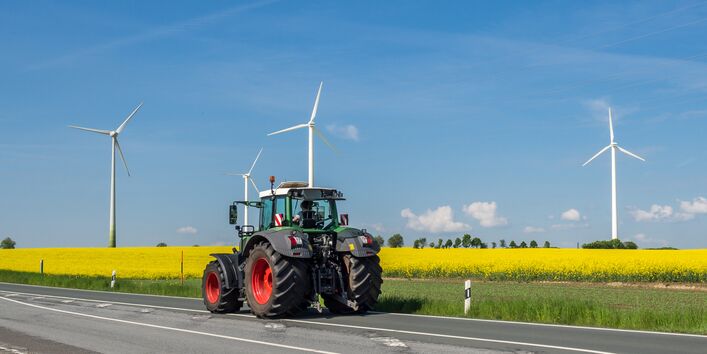 Ein Traktor vor einem Rapsfeld