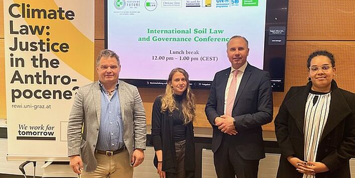 4 people standing in front of a video conferencing device.