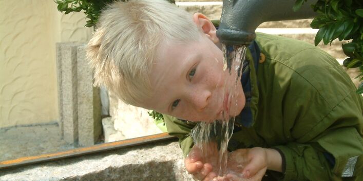 A boy drinking at the tap