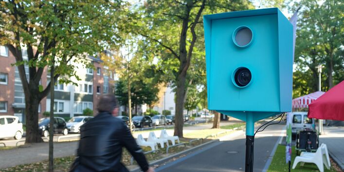 Radfahrer passiert "Fotokasten" der Bilder zum Geburtstag der Blauen Route schießt
