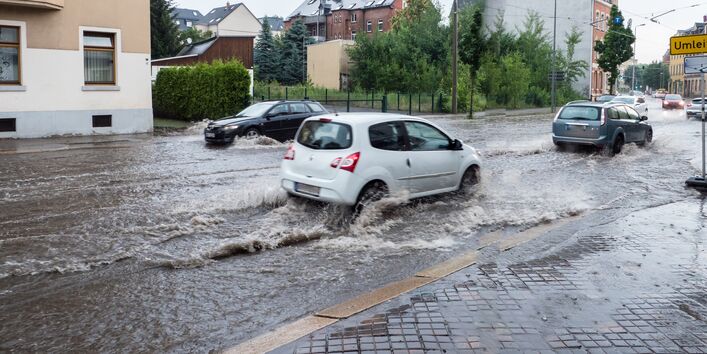 Auto fährt überflutete Straße entlang