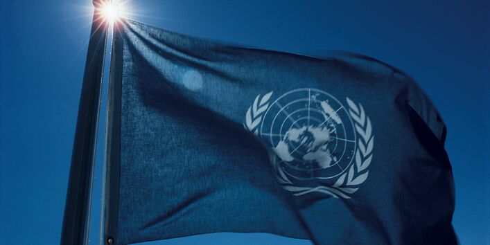 Wehende Flagge der Vereinten Nationen vor blauem Himmel