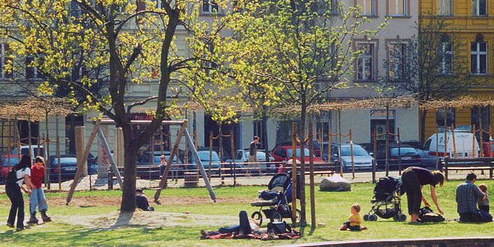 Erwachsene und Kinder halten sich auf einer städtischen Grünfläche auf.