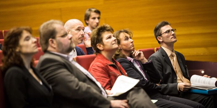 Die Workshopteilnehmer sitzen in Stuhlreihen und hören gebannt den Ausführungen der Vortragenden zu.