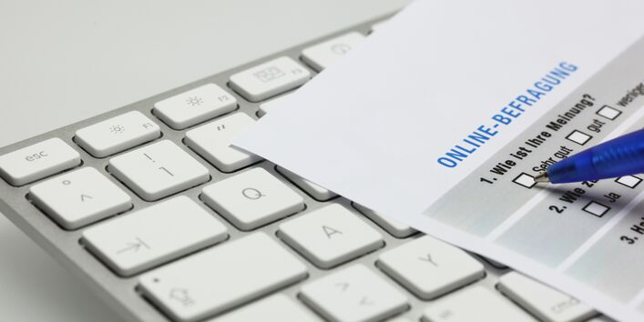 Tastatur auf der ein Blatt Papier liegt, auf dem erste Fragen einer Befragung zu erkennen sind