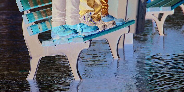People standing on a seat bench surrounded by water