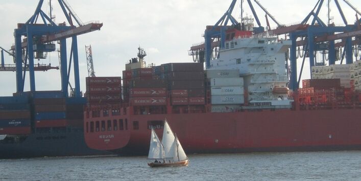 Sailing boat and container ship in the harbor of Hamburg