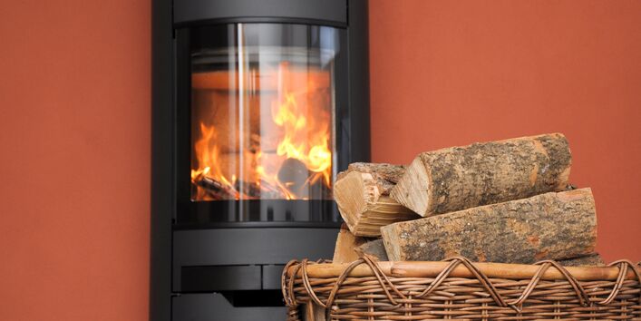 Kaminofen mit Feuer und Brennholzkorb
