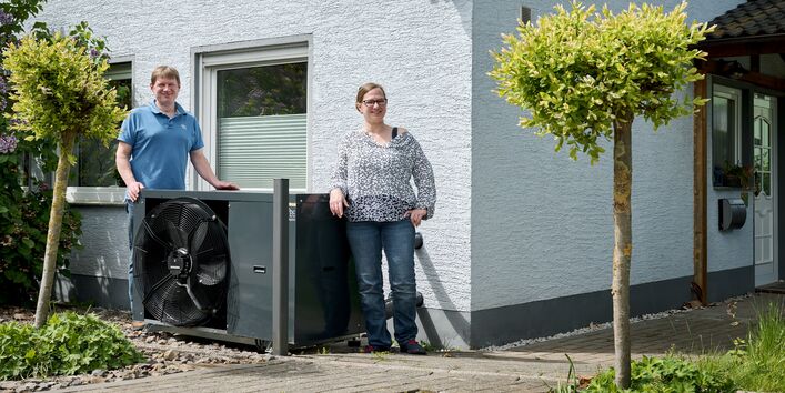 A couple standing next to their heat pump.