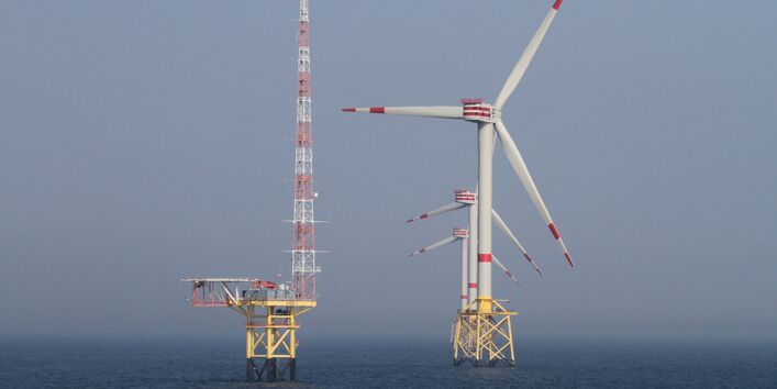 Blick auf drei Offshore Windenergieanlagen in Reihe und der Forschungsplattform FINO 1 daneben
