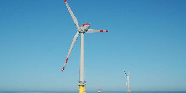Das Foto zeigt drei Strukturen des Offshore-Windpark Alpha Ventus. Im Vordergrund sieht man eine Windenergieanlage mit Monopile-Fundament. Im Hintergrund sieht man eine Anlage mit Jacket-Fundament (als Fachwerk konstruierte Gründungsstrukturen) und die Forschungsstation FINO1