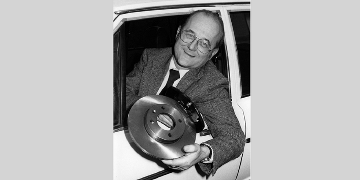 Von Lersner lehnt sich aus einem Autofenster und hält asbestfreie Bremsbeläge in die Kamera