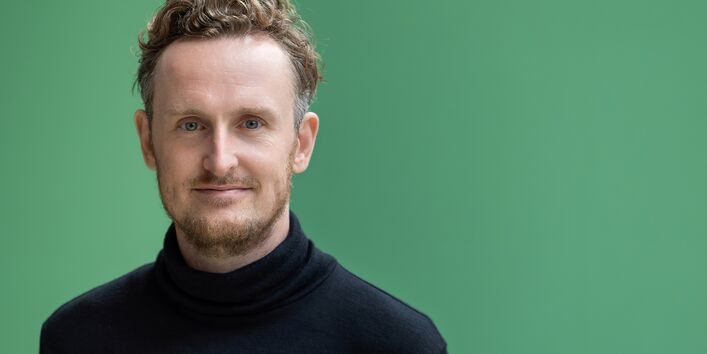 Dr. Jeremias Herberg, im Hintergrund eine grüne Wand